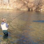 A boy fly fishing during a Montana spring break vacation to Big Sky.