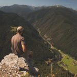 Man causally sitting at Storm castle overlooking mountain valley below