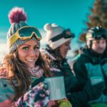 Friends enjoying the winter day on mountain. Drinking coffee or tea outdoors